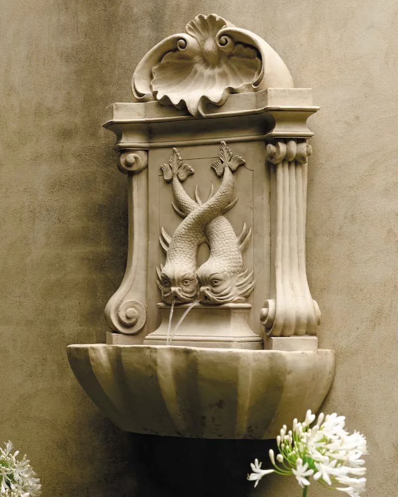 A carved wall fountain with two dolphins under a shell, above a basin
