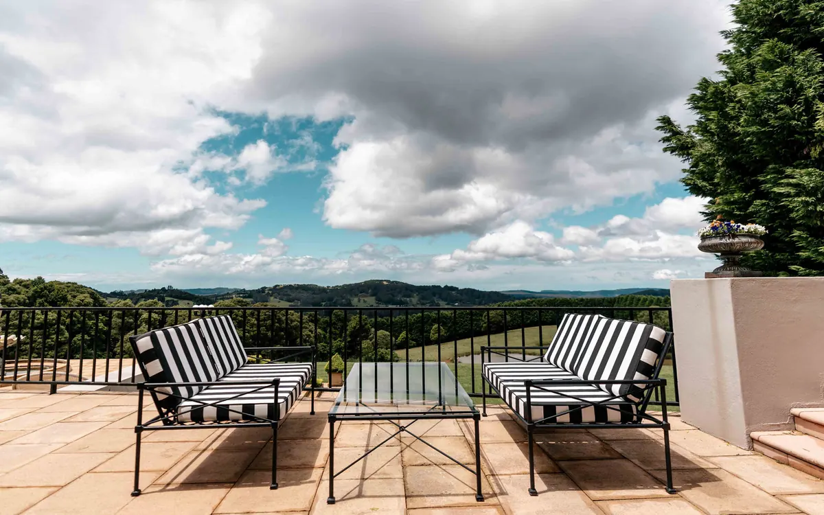 Black metal lounges with striped cushions on a terrace above rolling hills